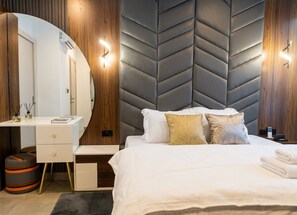 A hotel room with a bed, a desk, a mirror, and a modern wall design.