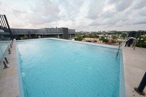 A rooftop swimming pool with a clear view of the cityscape in the background.