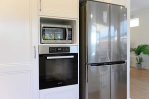 Uma cozinha equipada com micro-ondas embutido, forno e frigorífico de aço inoxidável.