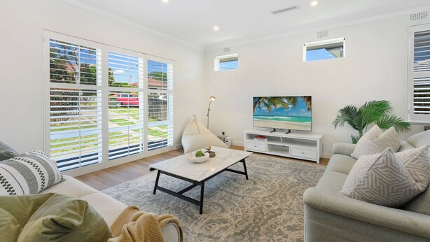 A living room with a sofa, a coffee table, a TV, and a large window with blinds. - Cosy 3 bedrooms Lane Cove 10 Mins to Sydney CBD (Lane Cove North)