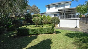 A modern two-story house with a garage, surrounded by well-maintained hedges and trees. - Cosy 3 bedrooms Lane Cove 10 Mins to Sydney CBD (Lane Cove North)