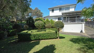 A modern two-story house with a garage, surrounded by well-maintained hedges and trees.