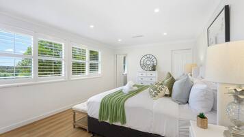 A bedroom with a bed, a dresser, a mirror, and a window with blinds.