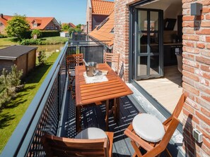 Ein Balkon mit Holztisch, Stühlen und Blick auf einen Fluss.