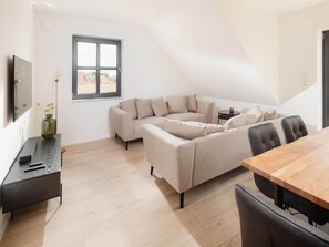 Ein modernes Wohnzimmer mit einer Eckcouch, einem Esstisch und einem kleinen Beistelltisch.