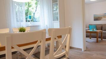A modern living room with a dining area, featuring a sofa, a coffee table, and a dining table with chairs.