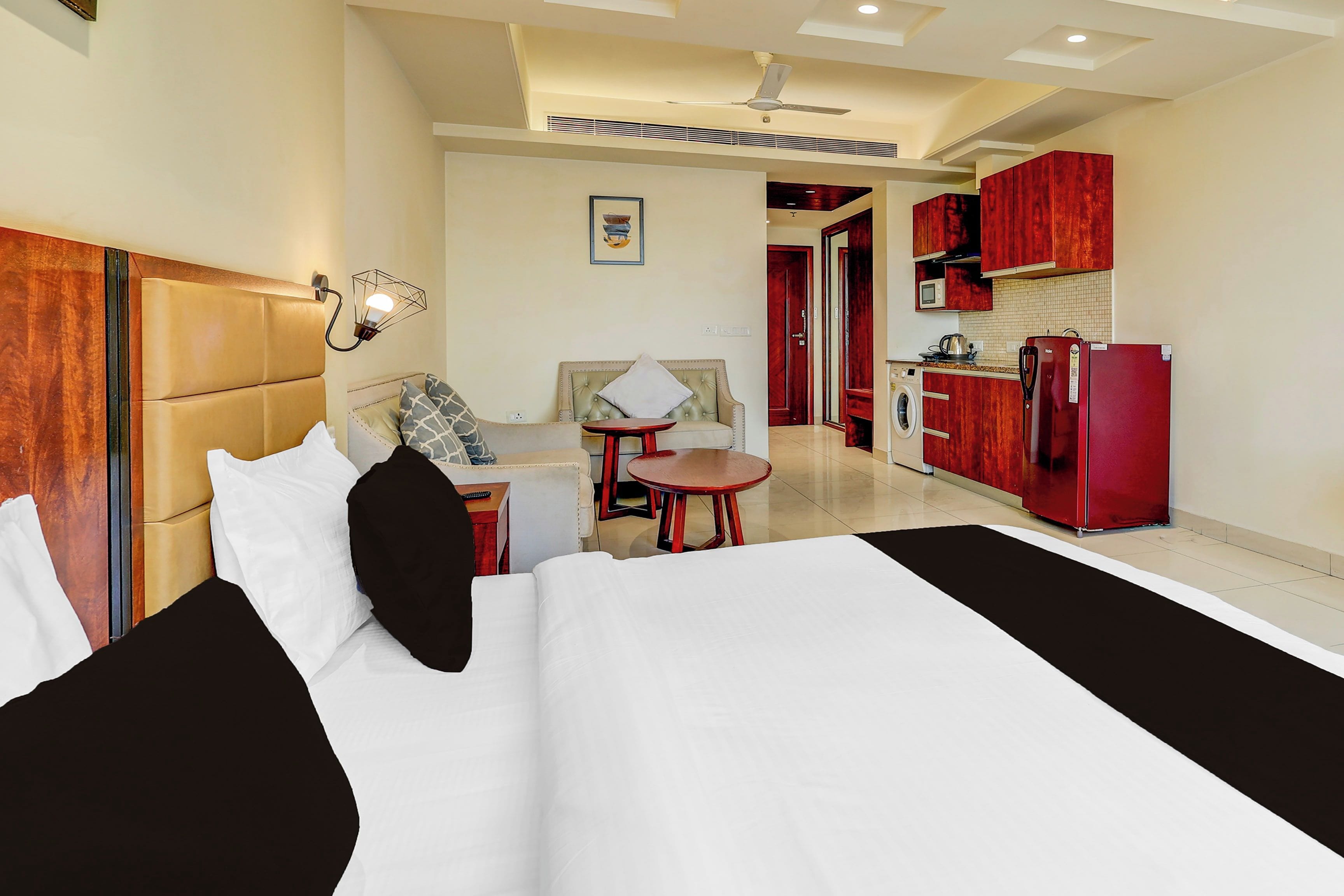 Une chambre d’hôtel comprenant un lit, un bureau, une chaise, une petite table et une kitchenette.