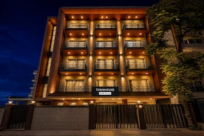 A multi-story hotel with a modern design, featuring balconies on each floor and a sign indicating it is serviced by YOYO. - Super Townhouse Oak Sector 39 Medanta (Gurugram)