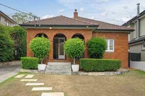 A residential house with a brick facade, a tiled roof, and a front entrance with a set of steps leading to a door. - Linley Point Luxury 5BR Home with Pool BBQ (Linley Point)