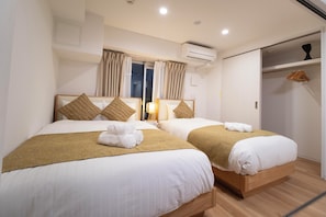 Ein Hotelzimmer mit zwei Betten, einem Kleiderschrank und einer Klimaanlage.