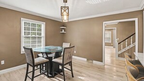 A dining area with a glass-top table, four chairs, a hanging light fixture, and a staircase leading to another level. - Newly renovated open concept home in Detroit, Mi. (Detroit)
