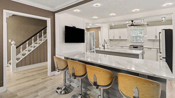 A modern kitchen with a central island, bar stools, and a flat-screen TV mounted on the wall. - Newly renovated open concept home in Detroit, Mi. (Detroit)