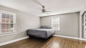 A bedroom with a bed, a ceiling fan, and two windows with blinds. - Newly renovated open concept home in Detroit, Mi. (Detroit)