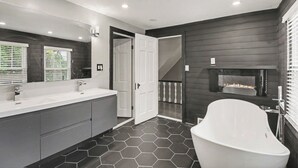 A modern bathroom with a large white bathtub, a double sink vanity, and a fireplace. - Newly renovated open concept home in Detroit, Mi. (Detroit)