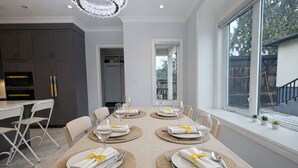 Un comedor moderno con una mesa dispuesta para cuatro, una cocina al fondo y un amplio ventanal con vistas.