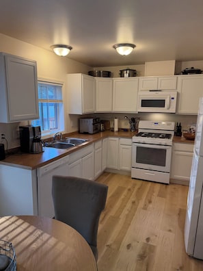A kitchen with white cabinets, a microwave, a stove, and a sink.