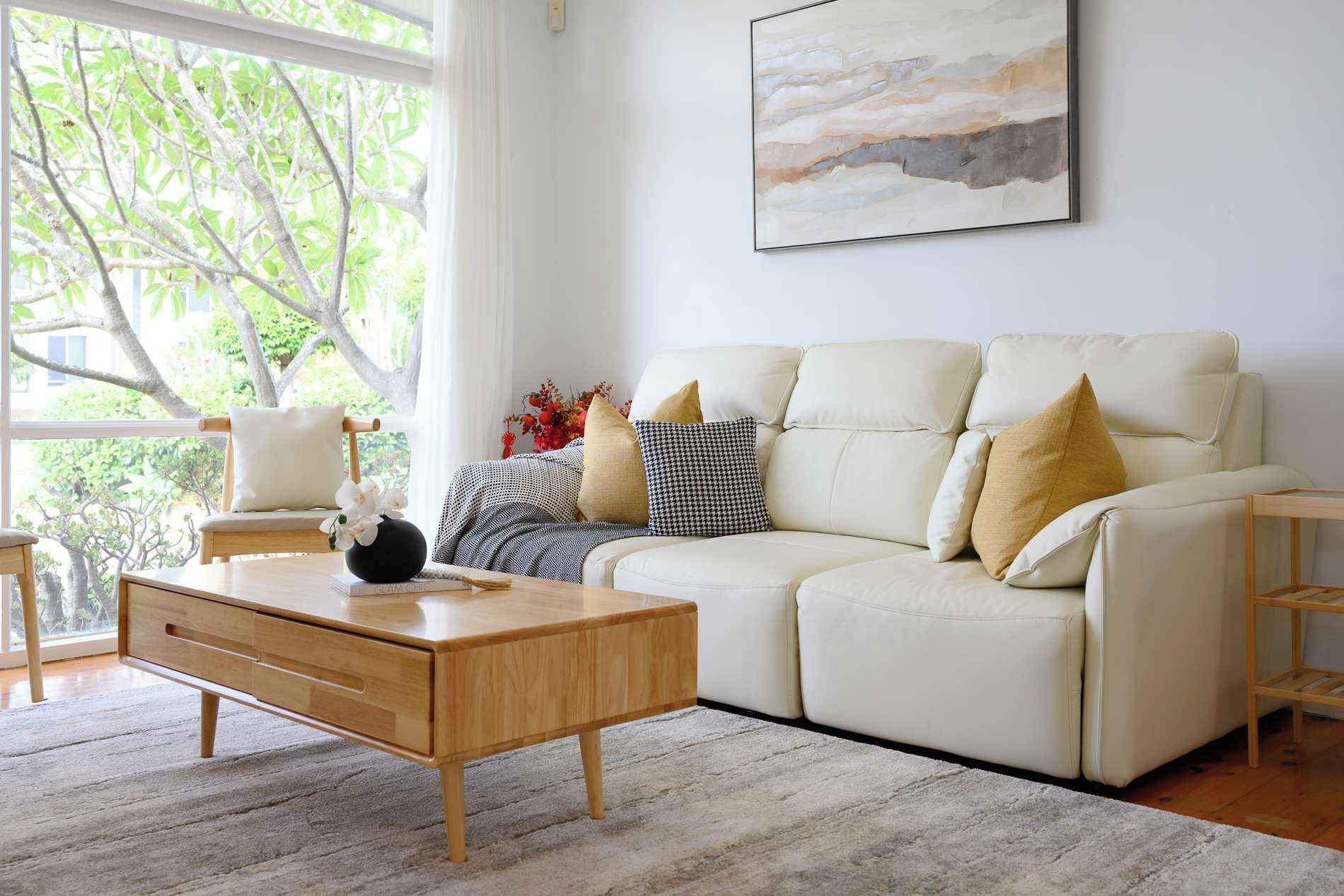 A modern living room with a sofa, coffee table, and a painting on the wall.