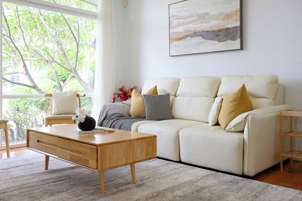 A modern living room with a sofa, coffee table, and a painting on the wall.