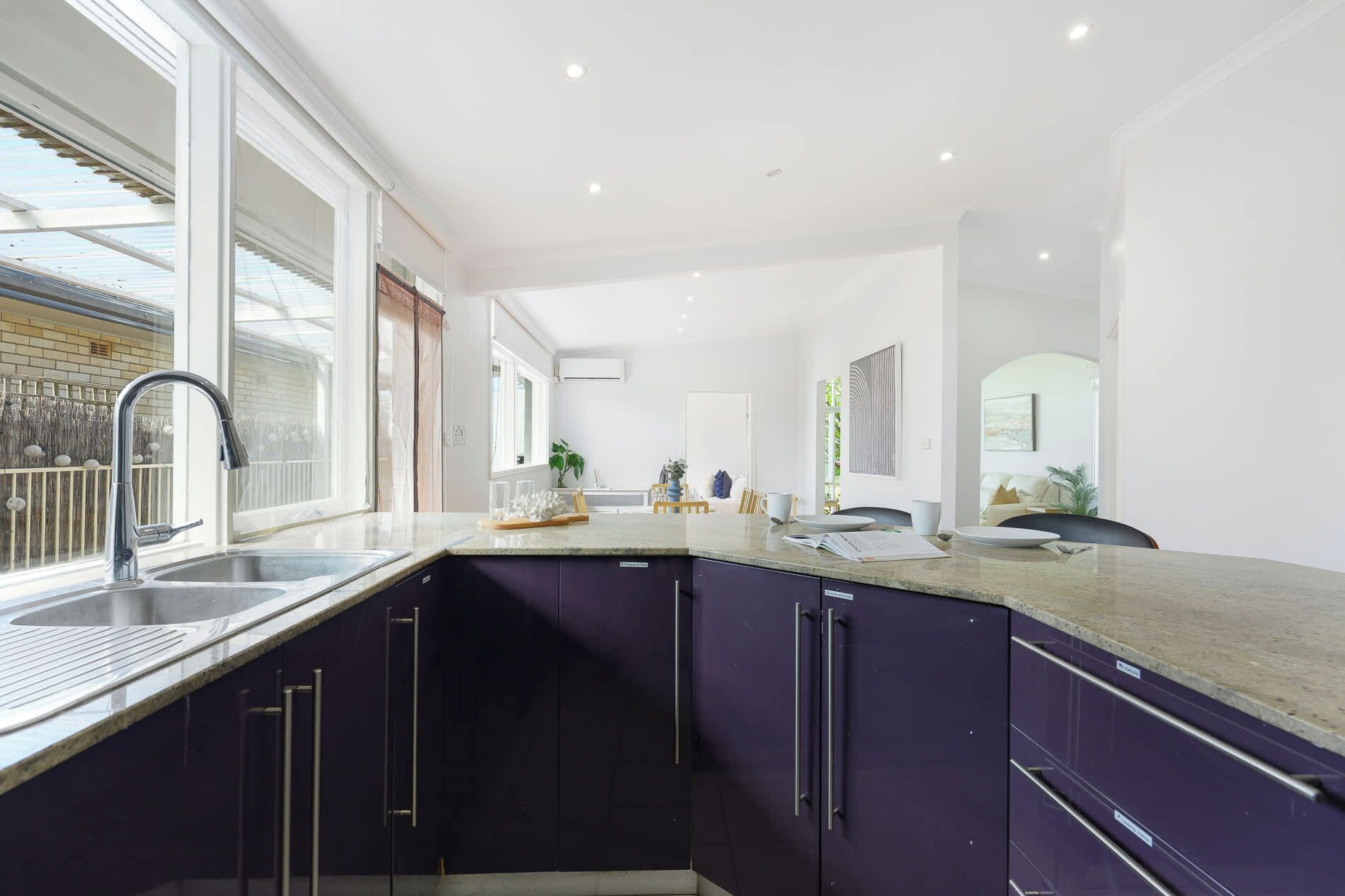 A modern kitchen with dark cabinets, a granite countertop, and a large window.