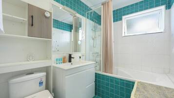 A bathroom with a shower, toilet, and sink.