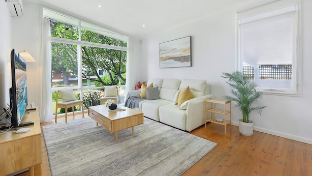 A modern living room with a sofa, coffee table, and a large window offering a view of greenery outside. - 4BR Marsfield Stay  Walk to Macquarie Uni Metro (Marsfield)
