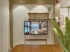 A television mounted on a wall displaying a library interior with bookshelves and seating areas. - SunYou Stay (Andong)