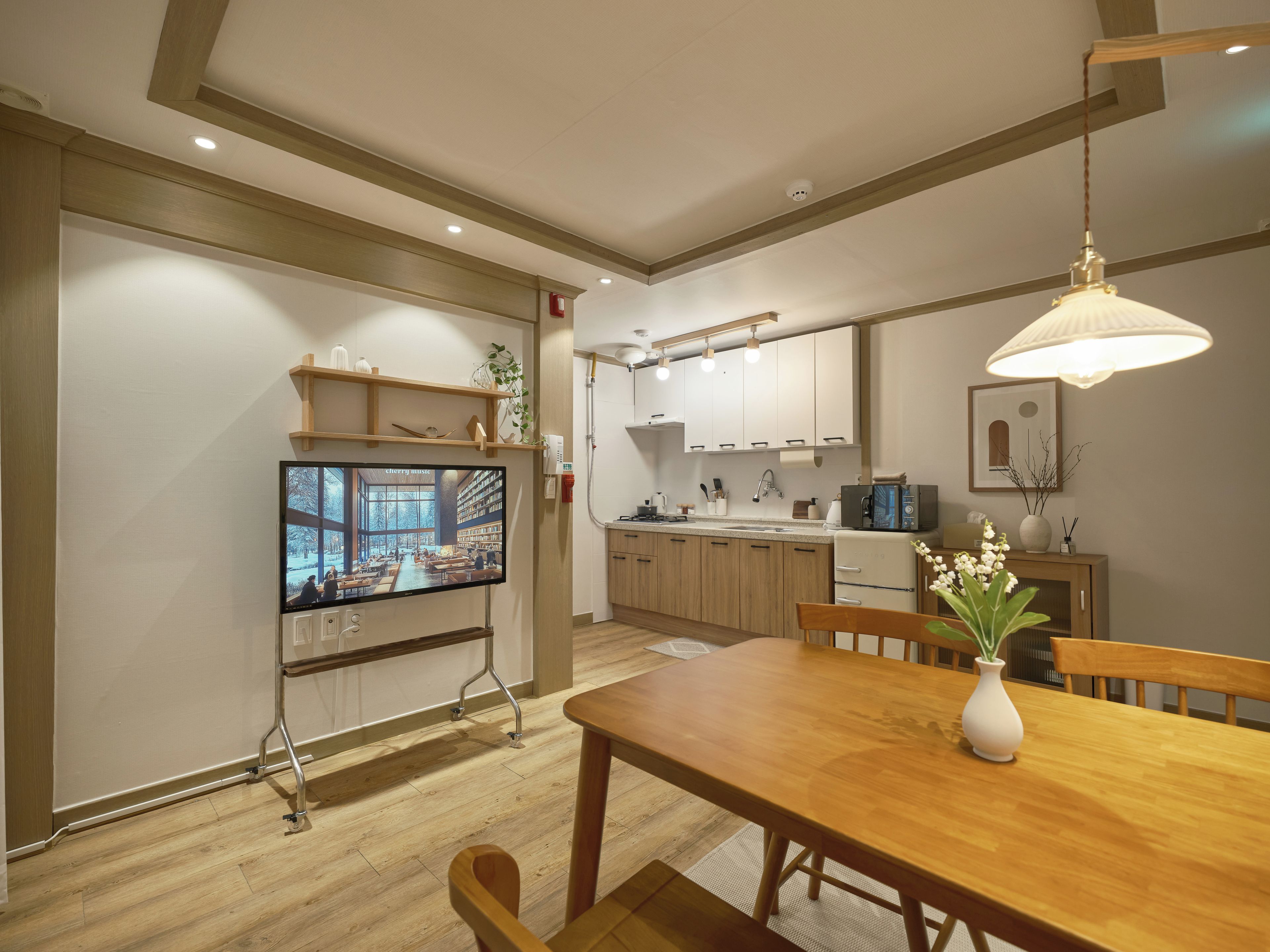 A modern kitchen with wooden cabinets, a built-in microwave, and a dining area with a wooden table and chairs.