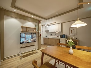 A modern kitchen with wooden cabinets, a built-in microwave, and a dining area with a wooden table and chairs. - SunYou Stay (Andong)