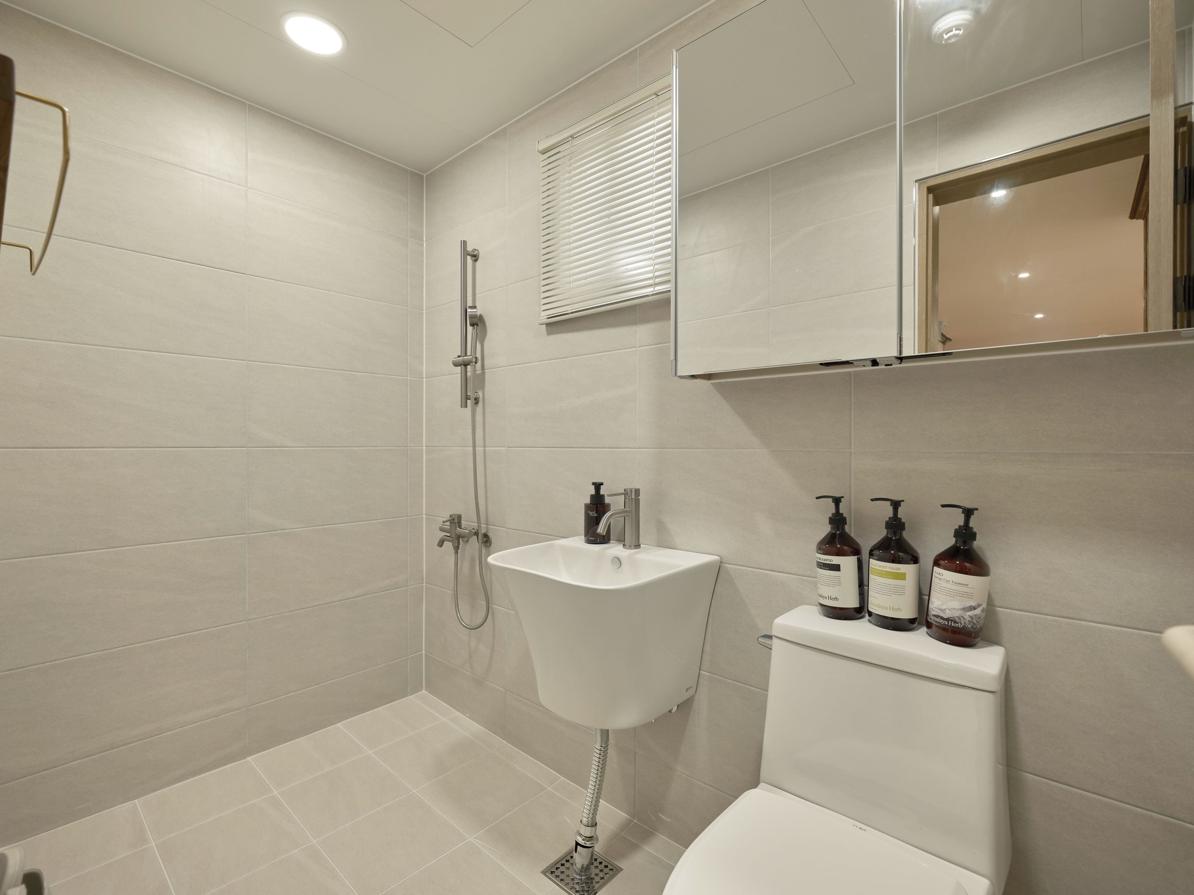 A modern bathroom with a shower, sink, and toilet.