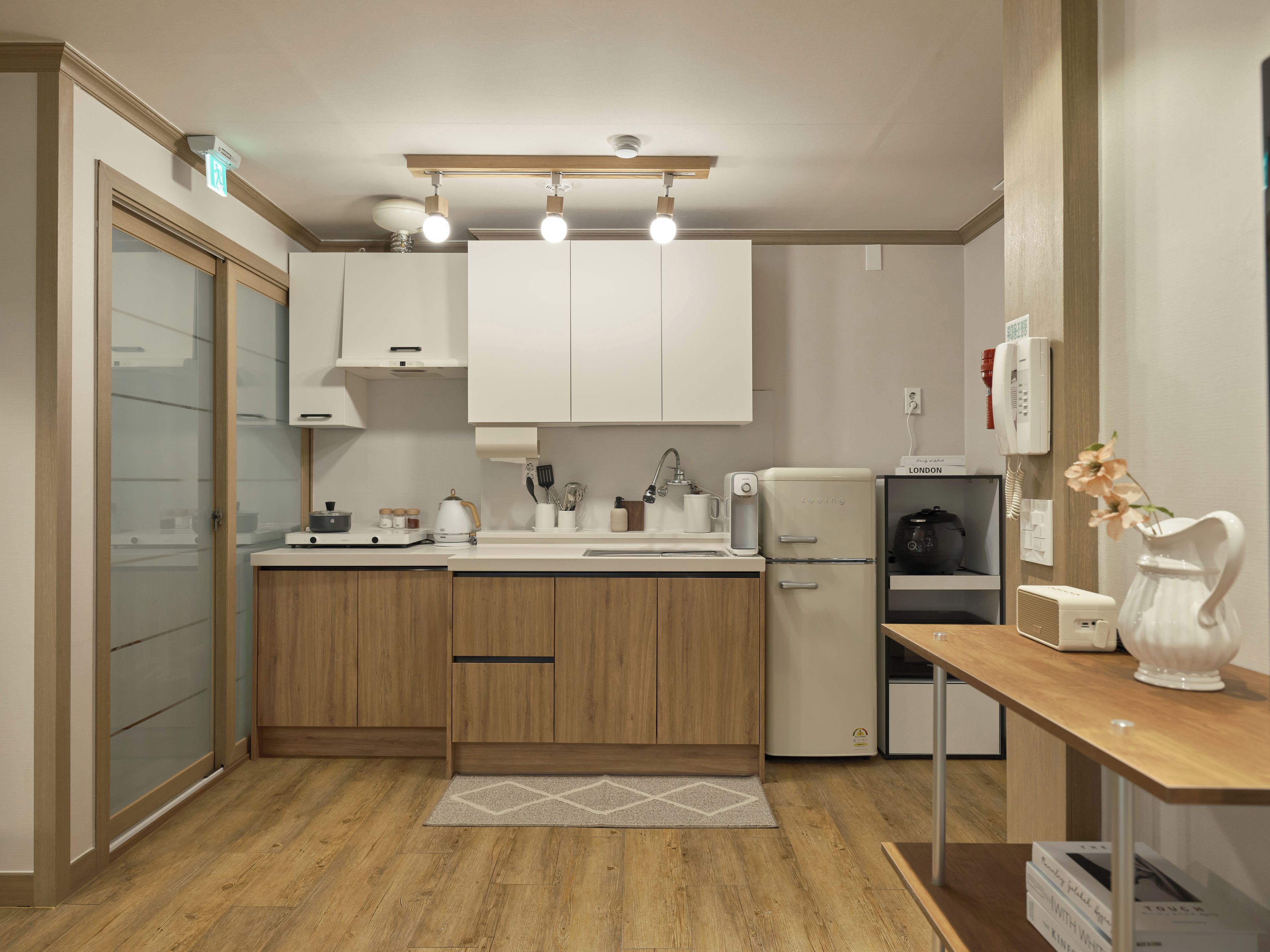 A modern kitchen with wooden cabinets, a built-in oven, a refrigerator, and a coffee machine.