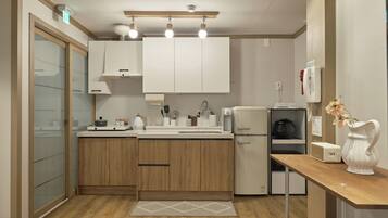 A modern kitchen with wooden cabinets, a built-in oven, a refrigerator, and a coffee machine.