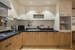 A modern kitchen with wooden cabinets, a built-in microwave, and a stainless steel sink. - SunYou Stay (Andong)