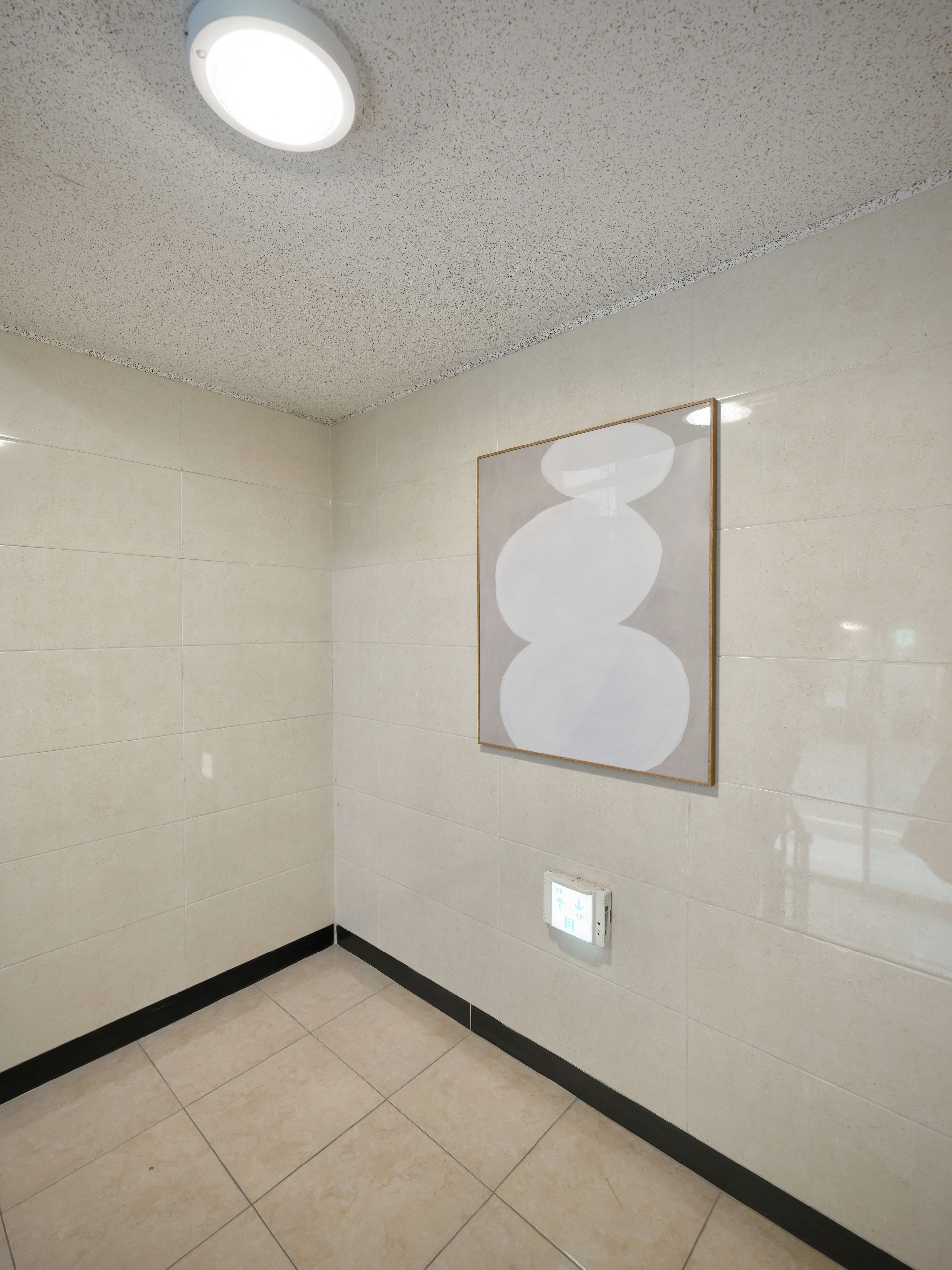A room with a tiled floor, a ceiling light, and a framed artwork on the wall.