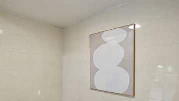 Een kamer met een betegelde vloer, een plafondlamp en een lijstwerk met een kunstwerk aan de muur.