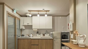 Eine moderne Küche mit Holzschränken, einem Einbauofen, einem Kühlschrank und einer Kaffeemaschine.