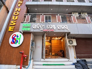 A building with a sign for 'Shree Marg A/C Non A/C Rooms' and a visible fire hydrant outside.