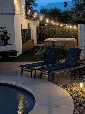 An outdoor pool area with lounge chairs, string lights, and a small garden with a hedge and plants. - Pool, Spa, & Games - Luxury Scottsdale Retreat Near Kierland (Scottsdale)