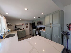 A modern kitchen with a marble countertop, stainless steel appliances, and light blue cabinetry. - Pool, Spa, & Games - Luxury Scottsdale Retreat Near Kierland (Scottsdale)