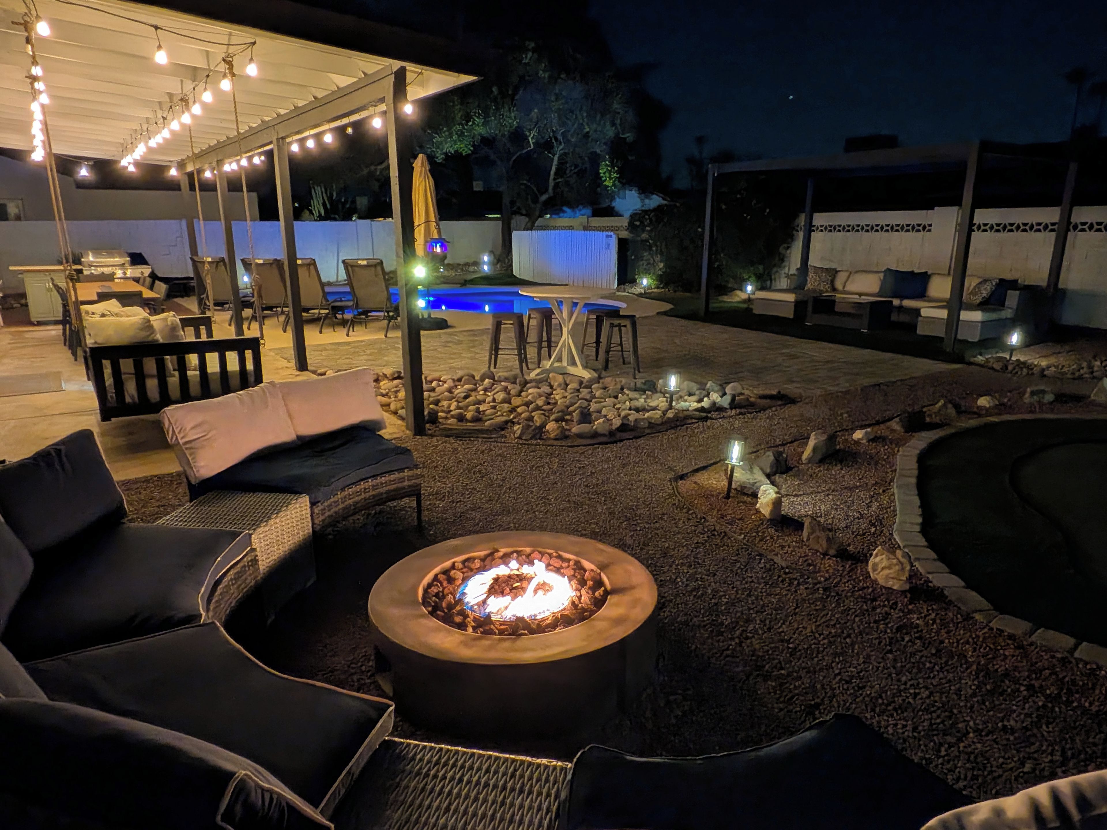 An outdoor patio area with seating, a fire pit, and a pool.