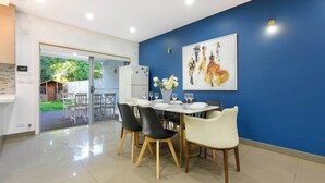 A dining area with a table set for four, chairs, and a vase with flowers. - Spacious 5BR Home Near Westmead and Parramatta (Northmead)