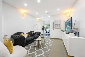 A modern living room with a sofa, a coffee table, and a TV mounted on the wall.
