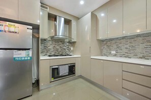 A modern kitchen with a stainless steel refrigerator, a built-in oven, and a tiled backsplash.