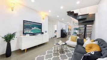 A modern living room with a flat-screen TV, a sofa, a coffee table, and a decorative rug.