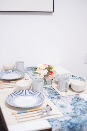 A dining table set with plates, cups, and a vase with flowers. - The Peak Namba Minami (Shikitsuhigashi, Naniwa Ward)