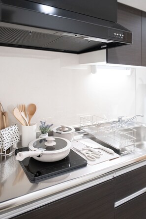 A modern kitchen with a black range hood, stainless steel appliances, and a white countertop. - The Peak Namba Minami (Shikitsuhigashi, Naniwa Ward)
