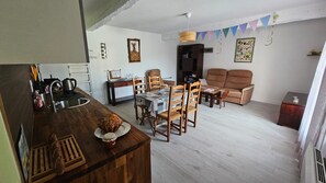 A cozy living room with a wooden dining table, two sofas, and a kitchen area with a sink and kettle. - Bénéjacq/Appartement pour 6 personnes avec Parking (BENEJACQ)