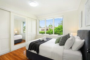A bedroom with a bed, a window, a mirror, and a door. - Vintage 5BR Retreat in Oatlands (Oatlands)
