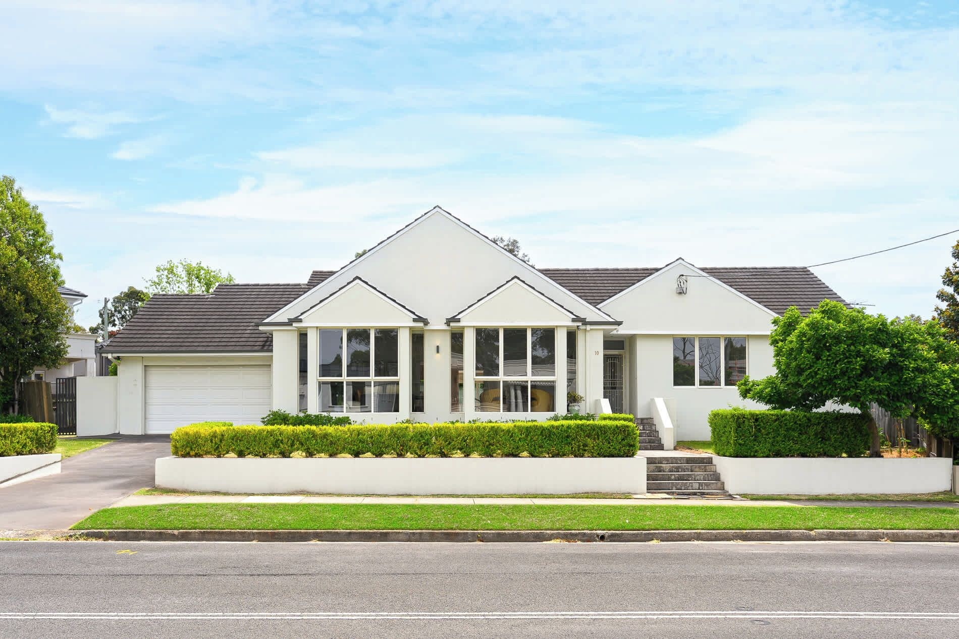 A two-story residential house with a garage, a front porch, and a well-maintained lawn.
