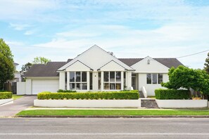 A two-story residential house with a garage, a front porch, and a well-maintained lawn. - Vintage 5BR Retreat in Oatlands (Oatlands)