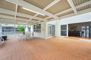 A covered patio area with a brick floor, white furniture, and a view of the outside. - Vintage 5BR Retreat in Oatlands (Oatlands)